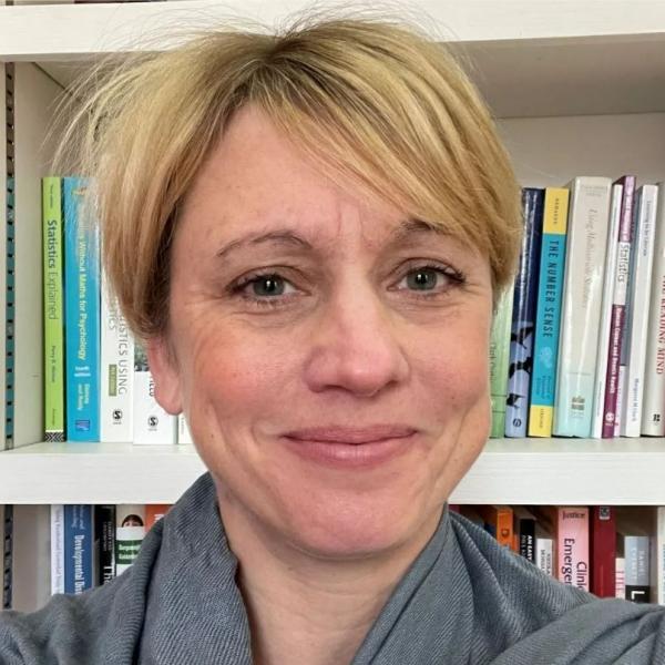 Profile picture of Claudine Bowyer-Crane smiling in front of a book case